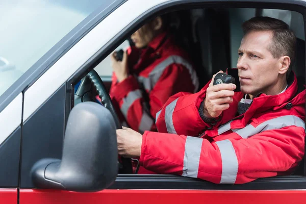 Male and female paramedics talking by portable radios — Stock Photo