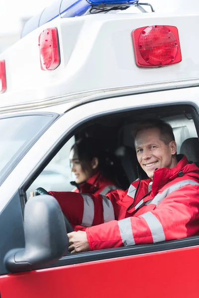 Felizes paramédicos masculinos e femininos sentados em ambulância — Fotografia de Stock