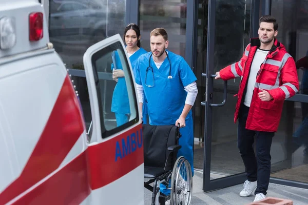 Sanitäter bewegen Rollstuhl vom Krankenhaus in Krankenwagen — Stockfoto