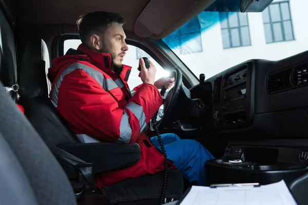 Young handsome male paramedic talking by portable radio — Stock Photo