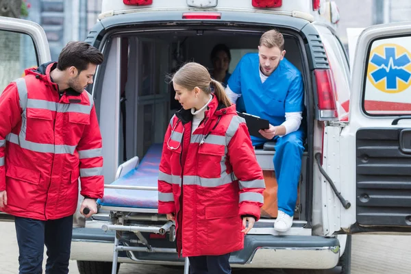 Paramedics moving out ambulance stretcher from car — Stock Photo