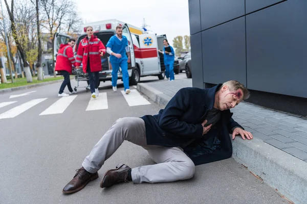 Injured man with wound on head lying on a street — Stock Photo