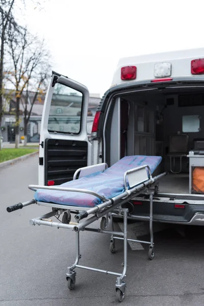 Abrir coche ambulancia y camilla en una calle - foto de stock
