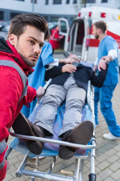 Парамедики перевозят больного человека на носилках скорой помощи — стоковое фото