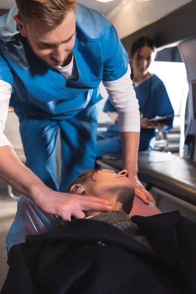 Paramedic checking pulse of injured middle aged man — Stock Photo