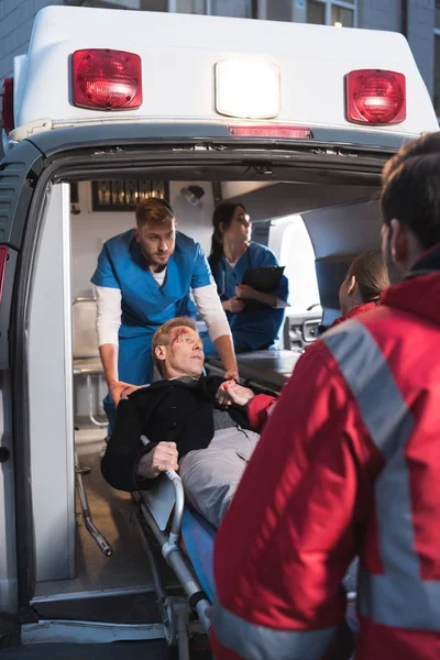 Paramedics moving injured man into ambulance — Stock Photo