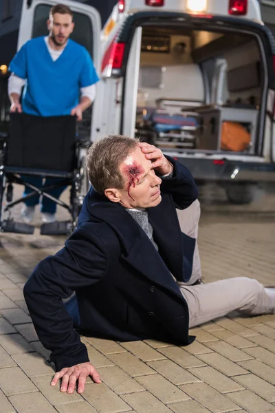 Doctor going to help wounded man lying on a street — Stock Photo