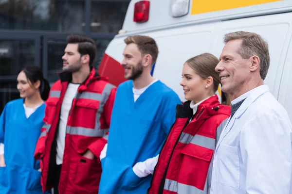 Ambulância médicos equipe de trabalho sorrindo e de pé na frente do carro — Fotografia de Stock