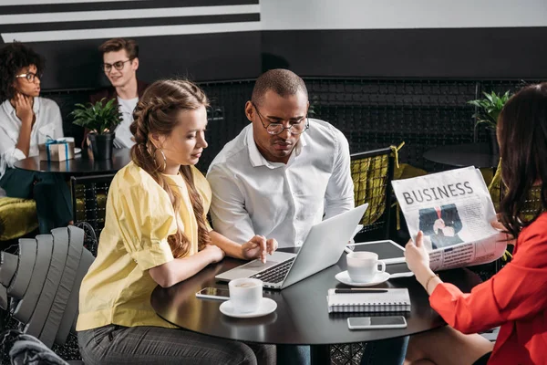 Jóvenes socios de negocios exitosos mirando juntos a la computadora portátil - foto de stock