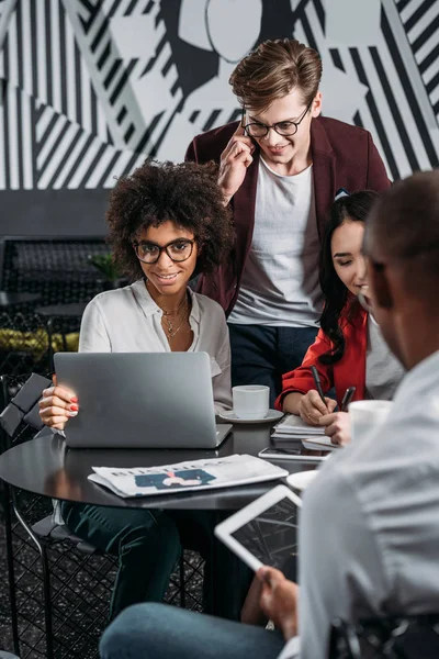 Multiethnic business partners working with laptop at cafe — Stock Photo