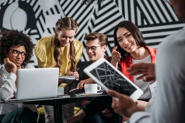 Geschäftspartner arbeiten zusammen, während der Mensch das Tablet im Vordergrund benutzt — Stockfoto