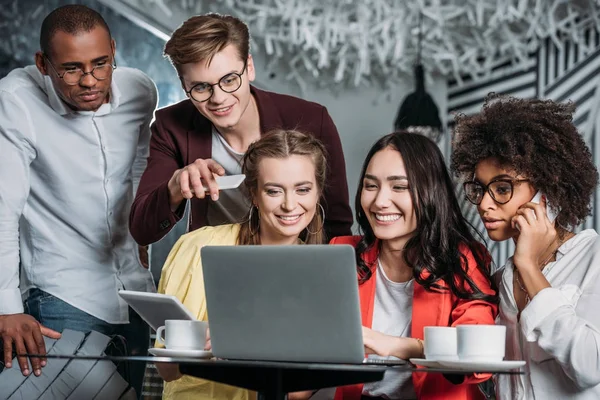 Multiethnische Gruppe junger Freunde blickt in Café auf Laptop — Stockfoto