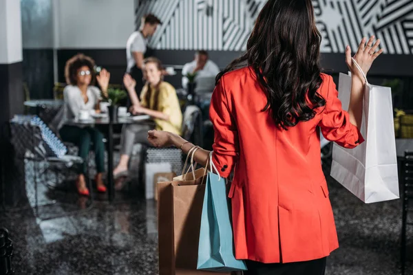 Donna con le borse della spesa andando ai suoi amici nel caffè — Foto stock