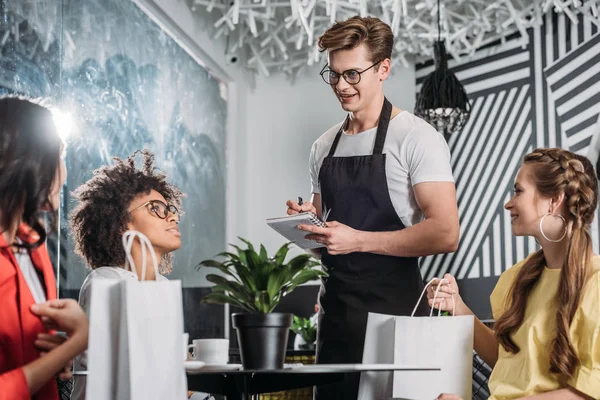 Grupo de mujeres multiétnicas con estilo haciendo orden en la cafetería - foto de stock