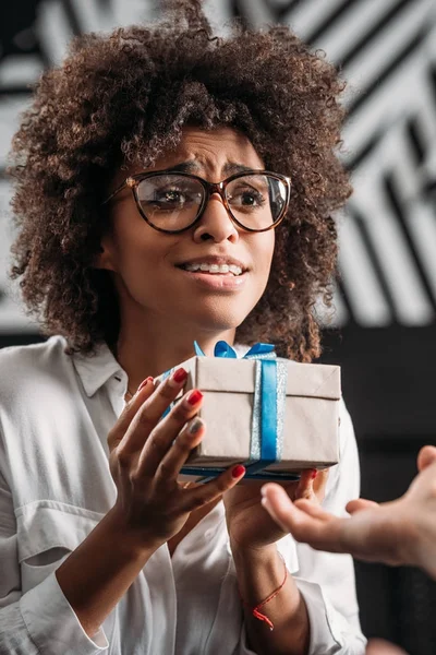 Beautiful happy african american woman carefully holding gift — Stock Photo