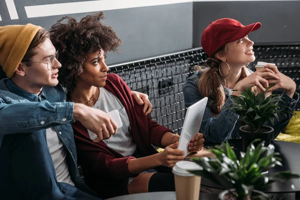 Grupo de personas con estilo multiétnico sentado en la cafetería moderna - foto de stock