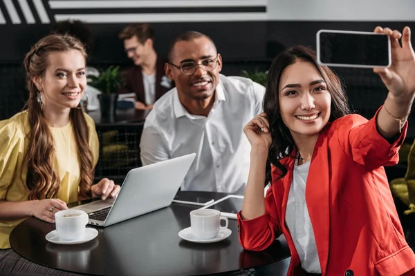 Grupo de socios comerciales multiétnicos tomando selfie en la cafetería - foto de stock