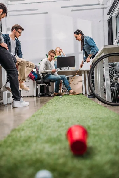 Collègues joyeux jouant au mini golf au bureau moderne — Photo de stock