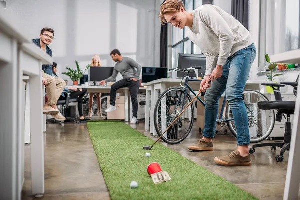 Pessoas felizes jogando em mini-golfe no escritório moderno — Fotografia de Stock