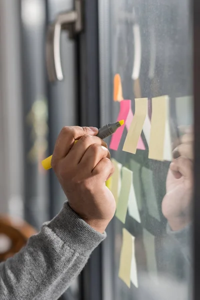 Abgeschnittenes Bild eines Mannes, der Notizen auf Aufklebern am Fenster macht — Stockfoto