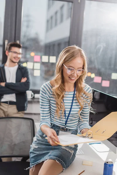 Young woman looking at folder with documents at modern office — Stock Photo