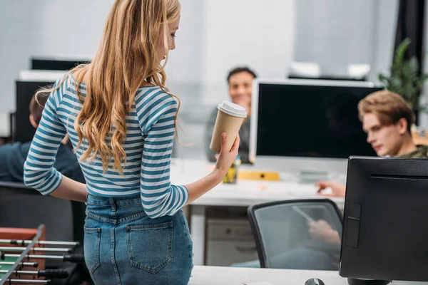 Vista trasera de la joven chica caucásica con taza de café en la oficina moderna - foto de stock