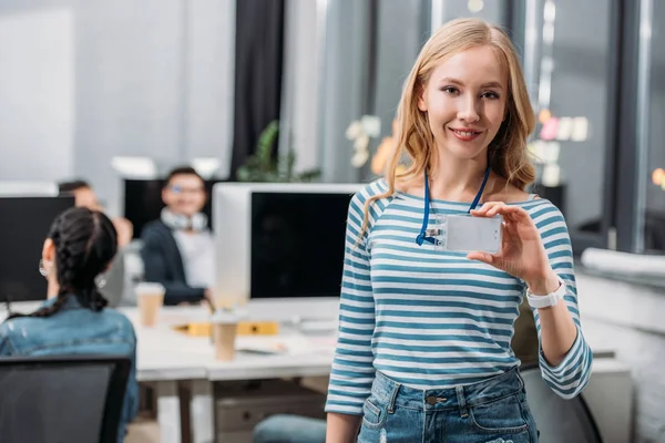 Joven caucásico chica mostrando nombre etiqueta en moderno oficina - foto de stock