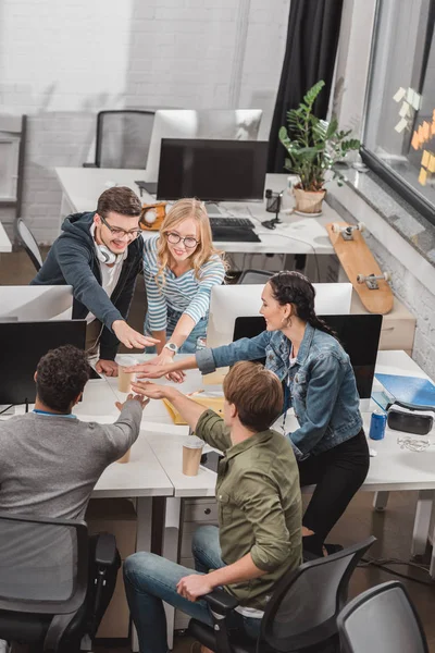 Cheerful multicultural business team making stack of hands at modern office — Stock Photo