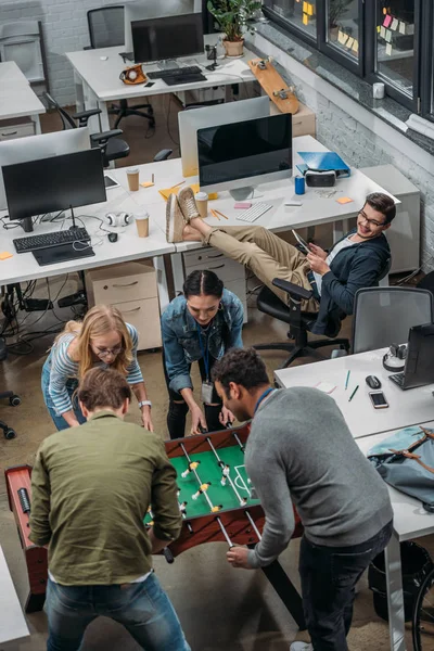 Multikulti-Menschen spielen im modernen Büro im Tischkicker — Stockfoto