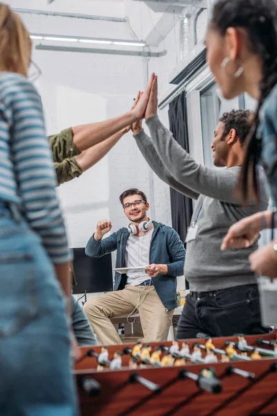 Colegas celebrando a vitória no futebol de mesa no escritório moderno — Fotografia de Stock