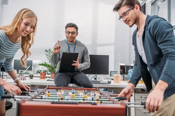 Young man and woman playing in table soccer at modern office — Stock Photo