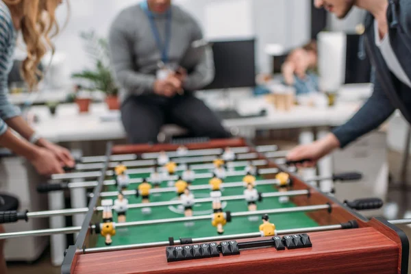 Imagen recortada de las personas que juegan en el fútbol de mesa en la oficina moderna - foto de stock