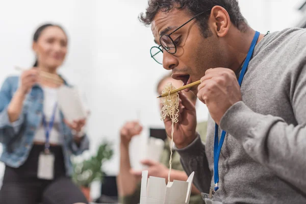 Hombre afroamericano comiendo comida tailandesa en oficina moderna - foto de stock