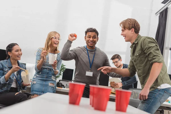 Jovens trabalhadores atraentes jogando cerveja pong no escritório moderno depois do trabalho — Fotografia de Stock