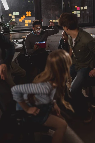 Young man spooking his colleagues in office at nighttime — Stock Photo