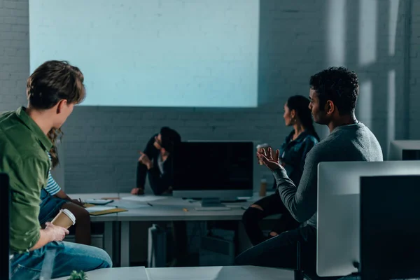People watching presentation in office at nighttime. blank screen — Stock Photo