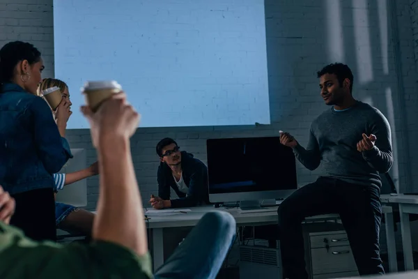 Cropped image of people in office at nighttime with coffee cups — Stock Photo