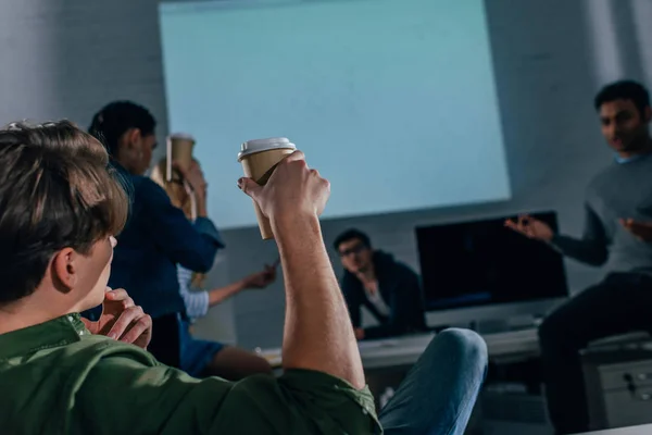 Imagen recortada de las personas en la oficina por la noche con tazas de café - foto de stock