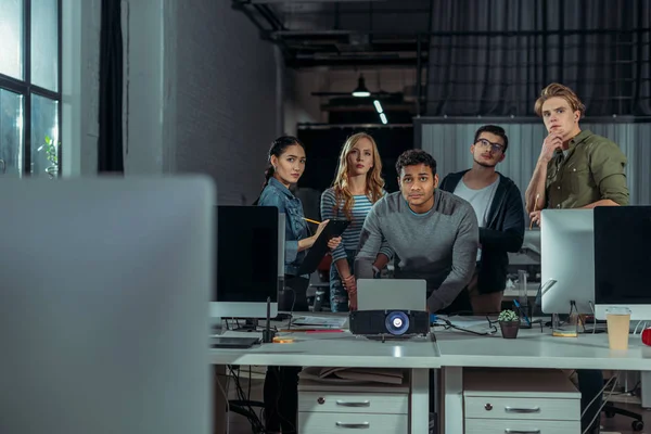 Junge Leute beobachten Präsentation im modernen Büro in der Nacht — Stockfoto