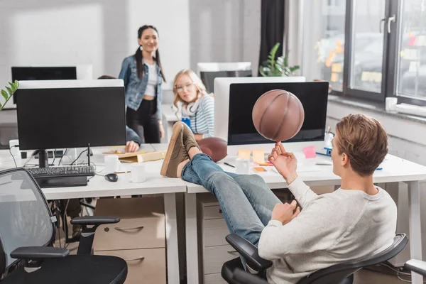 Mujeres viendo a hombre spinning bola en oficina - foto de stock