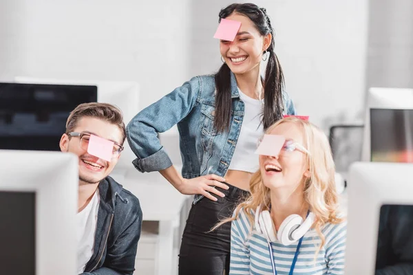 Personnes heureuses avec des autocollants sur les têtes au bureau moderne — Photo de stock