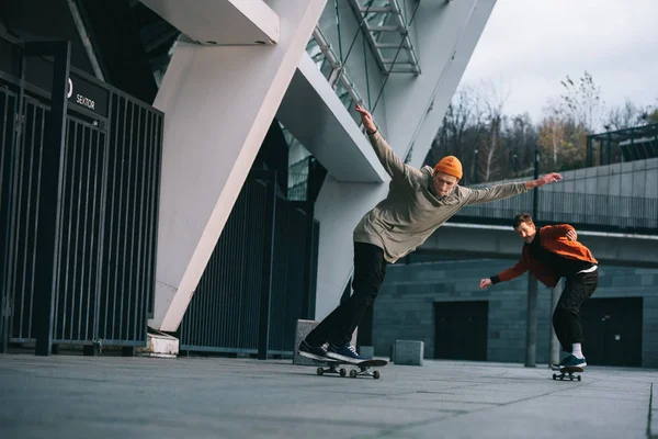 Hombres jóvenes montando monopatines en ubicación urbana - foto de stock