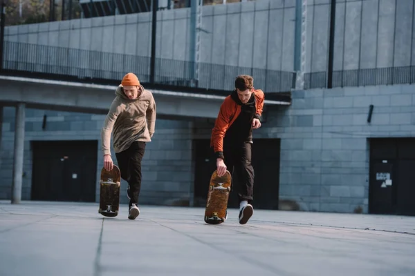 Jeunes hommes en tenue streetwear à cheval skateboards en milieu urbain — Photo de stock