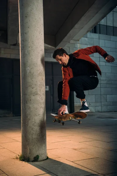 Bello giovane skateboarder esecuzione salto trucco in posizione urbana — Foto stock