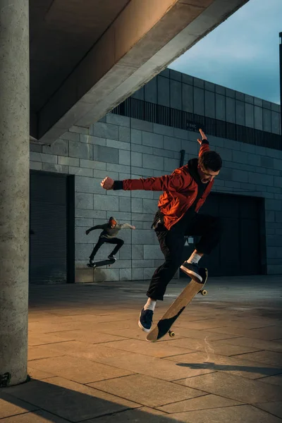 Skatistas realizando truques de salto juntos em local urbano — Fotografia de Stock