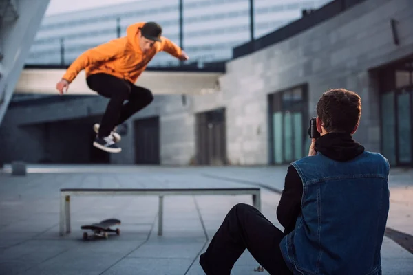 Homme prenant des photos de skateboarder sautant par-dessus le banc — Photo de stock