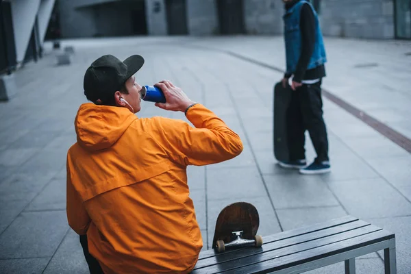 Skateboarder sitzt auf Bank und trinkt Wasser — Stockfoto