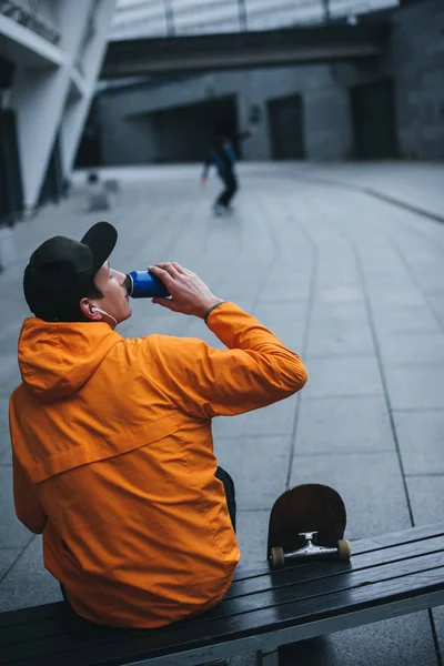 Skatista beber água e relaxar no banco após passeio — Fotografia de Stock