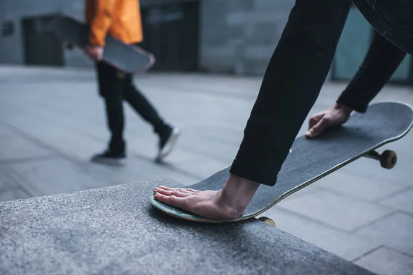 Cropped shot of man fixing skateboard with stone wall corner — Stock Photo