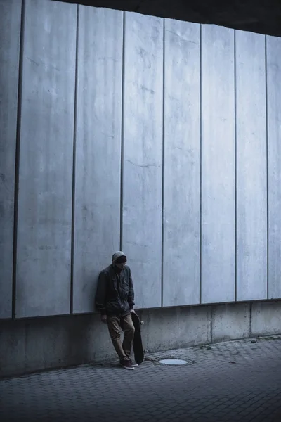 Skateboarder with board leaning back on grey concrete wall — Stock Photo